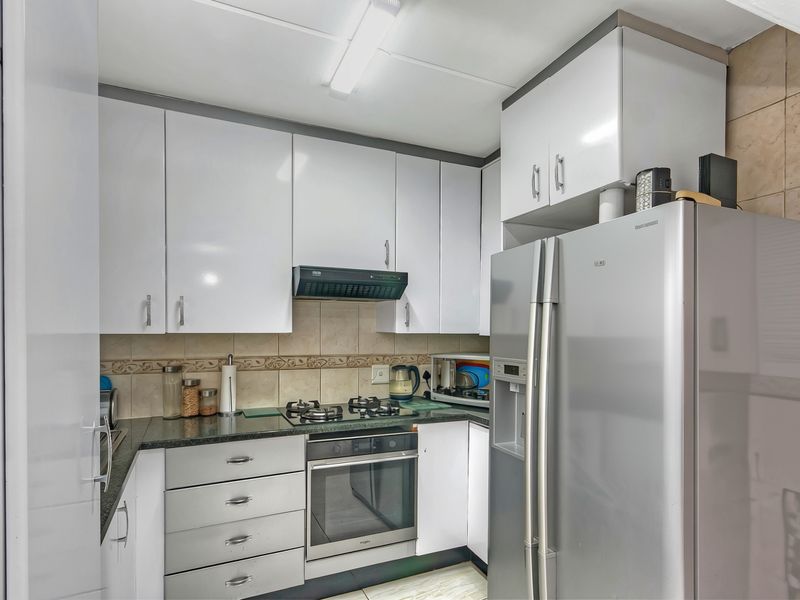 Compact kitchen featuring white cabinetry, granite countertops, a gas hob, built-in oven, and tiled backsplash.
