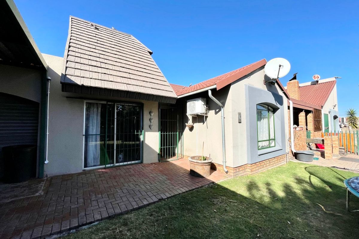 Rear exterior view of the flat featuring a brick paved patio, sliding glass door access, and a small private garden area.