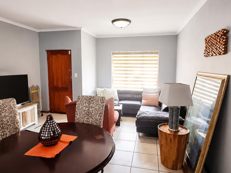 Open plan living and dining area featuring tiled flooring, neutral wall finishes, and natural light through a window with fitted blinds.