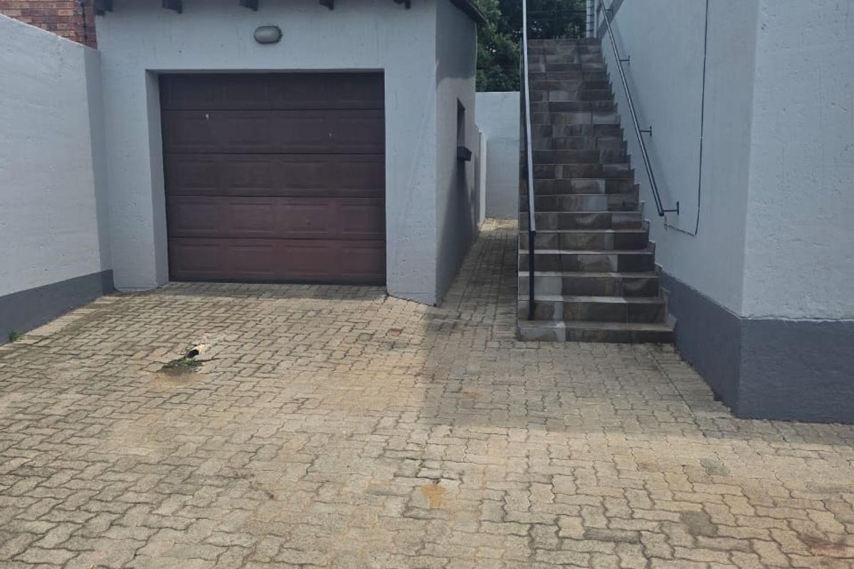 Exterior view of the property featuring a single garage, paved driveway, and an external staircase leading to the upper level.