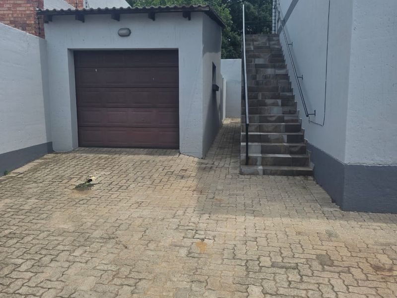 Exterior view of the property featuring a single garage, paved driveway, and an external staircase leading to the upper level.