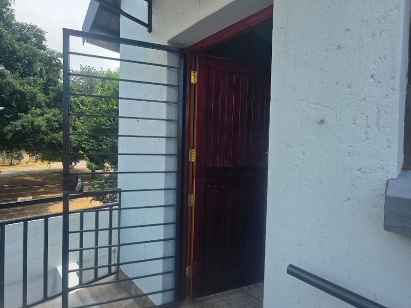Entrance area featuring a security gate, timber door, tiled flooring, and a protective awning over the doorway.