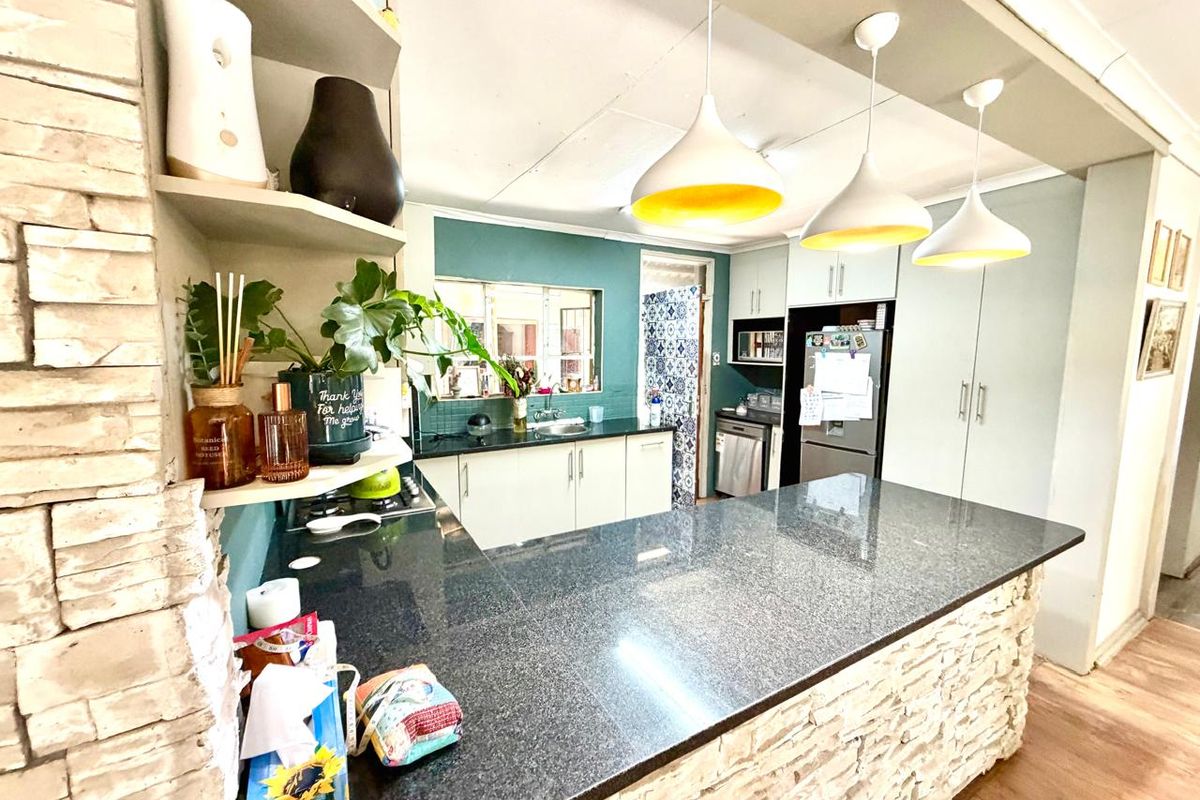 A functional kitchen featuring a stone-clad breakfast bar, granite countertops, ample cabinetry, and modern pendant lighting, creating a warm and inviting culinary space.