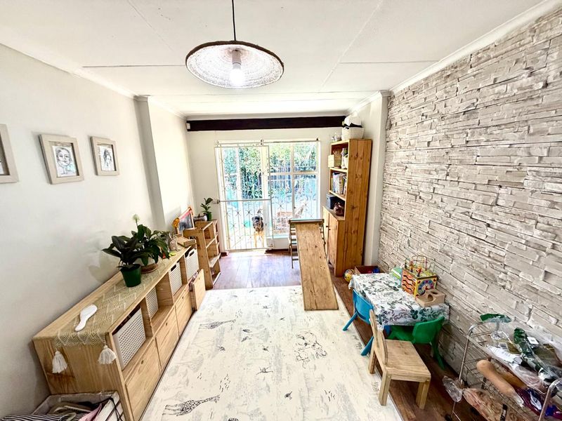 A living area featuring a textured stone veneer accent wall, laminate flooring, and a sliding glass door providing access to the exterior.