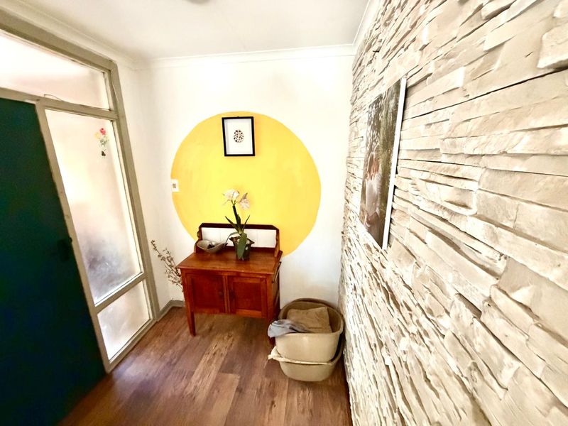 Entrance foyer featuring a textured stacked stone feature wall, laminate flooring, and a glass panel door providing natural light.