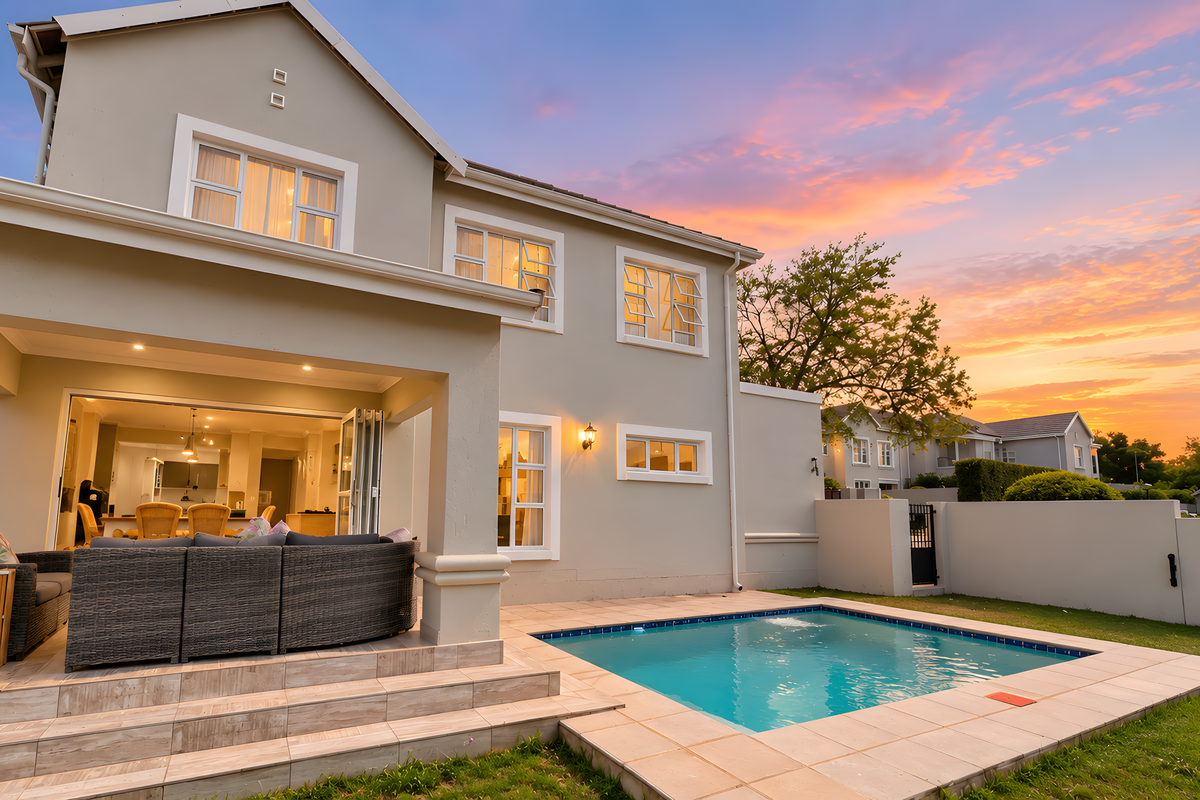 Rear view of the townhouse featuring a covered patio, a private swimming pool, and well-maintained exterior finishes at sunset.