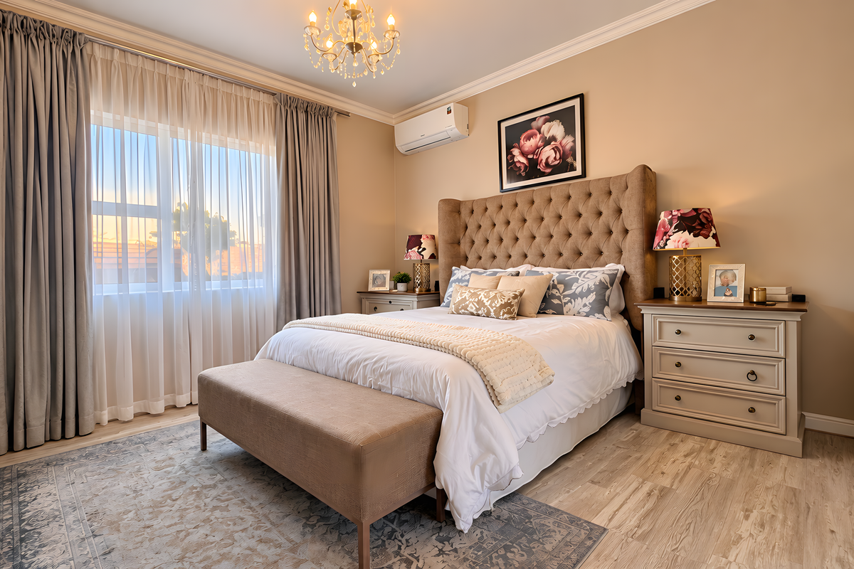 A well-maintained bedroom featuring laminate flooring, crown molding, a split-system air conditioner, and built-in wardrobe storage.