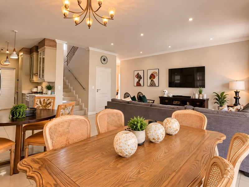 Spacious open-plan living and dining area featuring a modern kitchen, staircase, and neutral finishes, creating a bright and functional home layout.