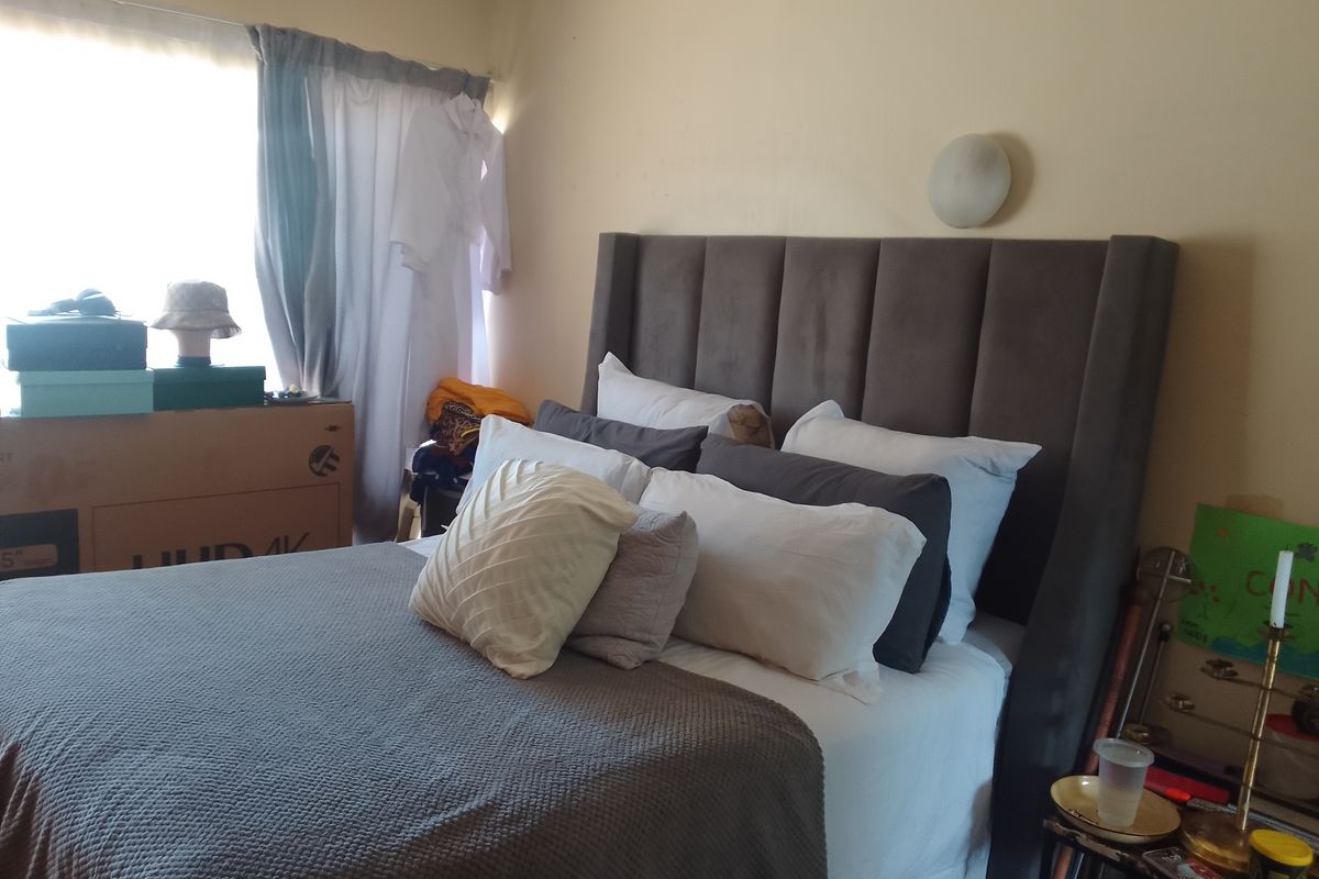 A bedroom featuring a neutral wall finish and a wall-mounted light fixture, providing a functional space for rest.