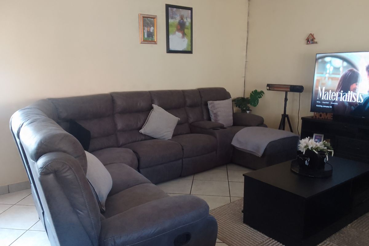 A comfortable living room featuring neutral wall tones and ceramic floor tiles, providing a functional and inviting space for relaxation.