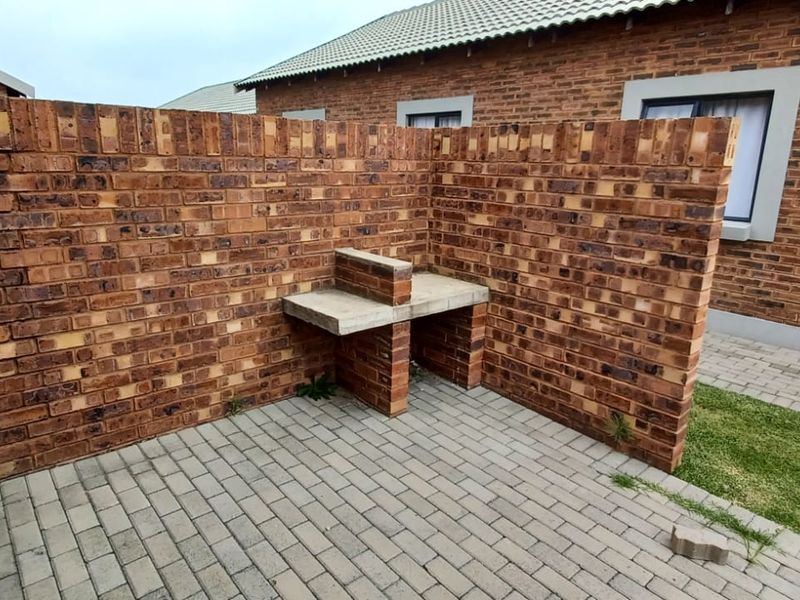 A private rear courtyard featuring a built-in facebrick braai area and paved patio space, ideal for outdoor entertaining.