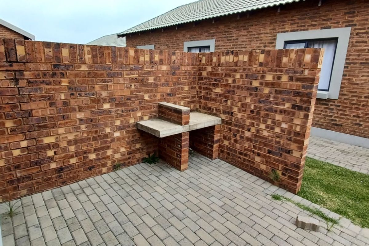 A private rear courtyard featuring a built-in facebrick braai area and paved patio space, ideal for outdoor entertaining.