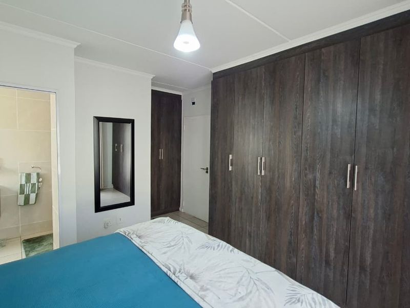 Bedroom featuring extensive dark wood built-in cupboards and direct access to an en-suite bathroom.
