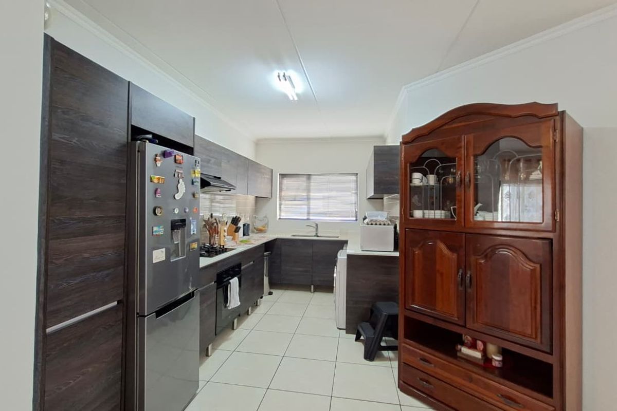 A functional kitchen featuring dark wood cabinetry, built-in appliances, and tiled flooring, offering a clean and practical workspace.