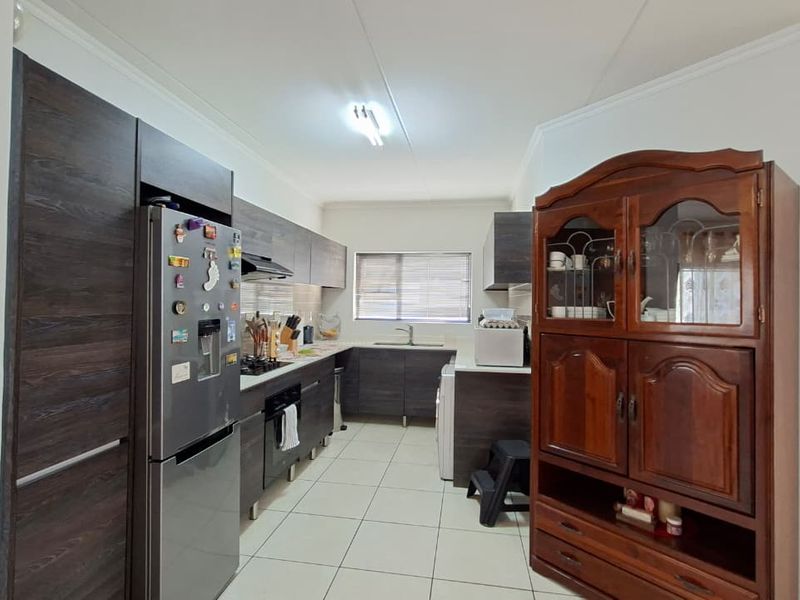 A functional kitchen featuring dark wood cabinetry, built-in appliances, and tiled flooring, offering a clean and practical workspace.