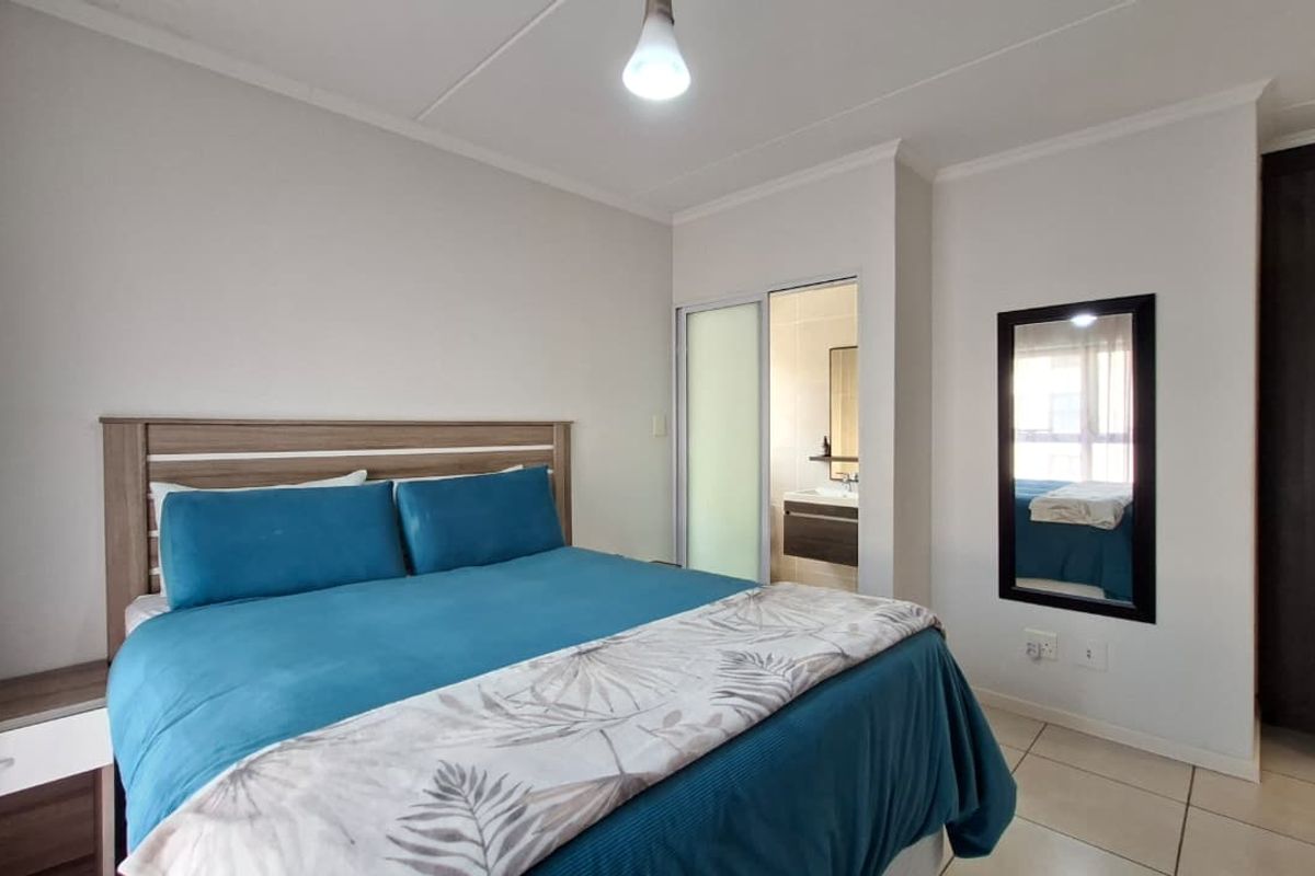 A well-maintained bedroom featuring tiled flooring and a convenient sliding door providing direct access to an en-suite bathroom.