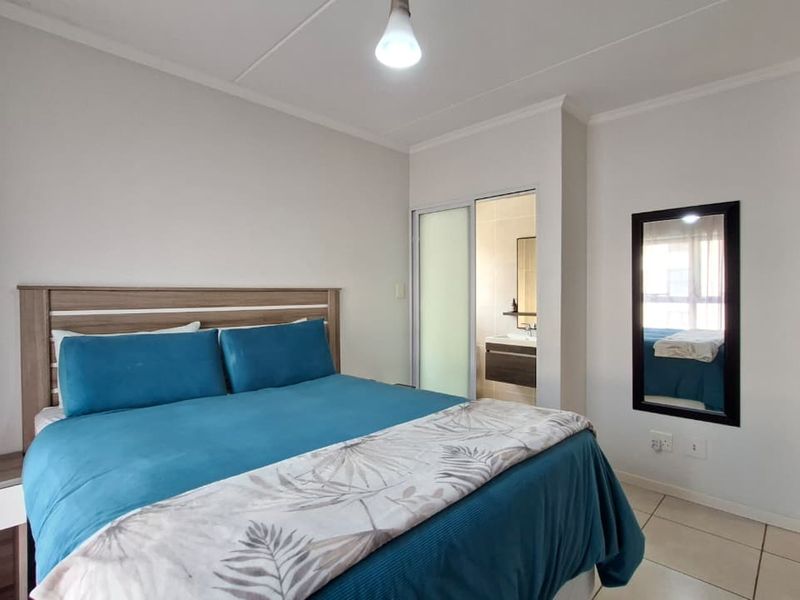 A well-maintained bedroom featuring tiled flooring and a convenient sliding door providing direct access to an en-suite bathroom.
