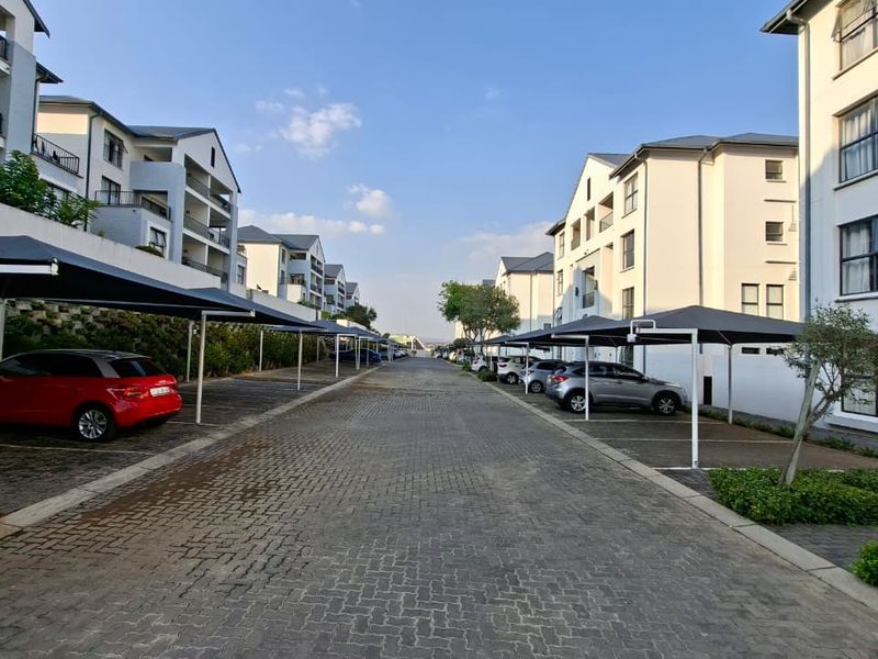 View of the apartment complex driveway featuring paved surfaces and covered parking bays for residents.