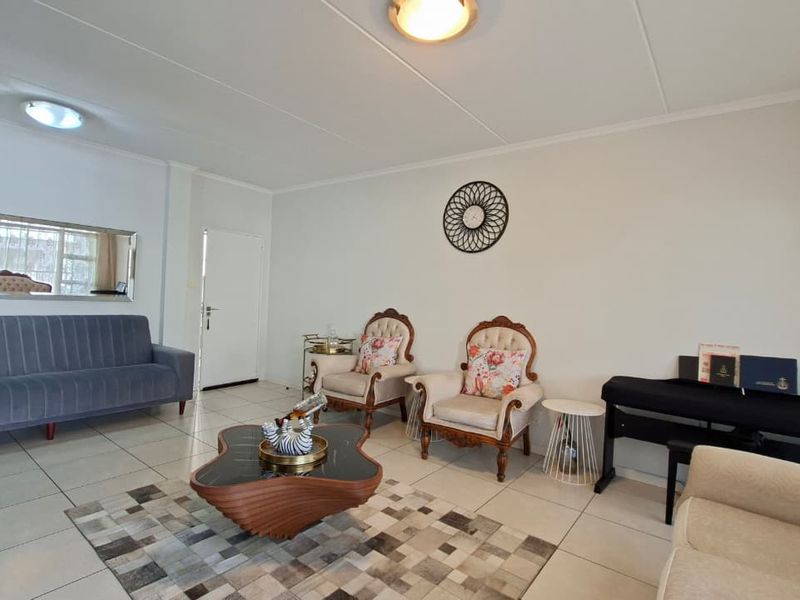 A spacious living room featuring neutral tiled flooring and bright overhead lighting, providing a clean and versatile foundation for interior design.