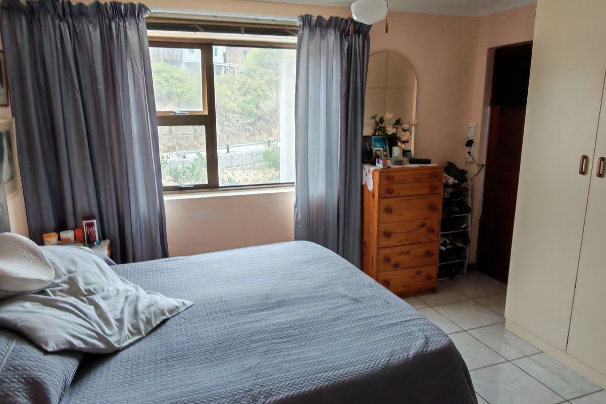 A bedroom featuring tiled flooring, built-in cupboards, and a window with natural light.
