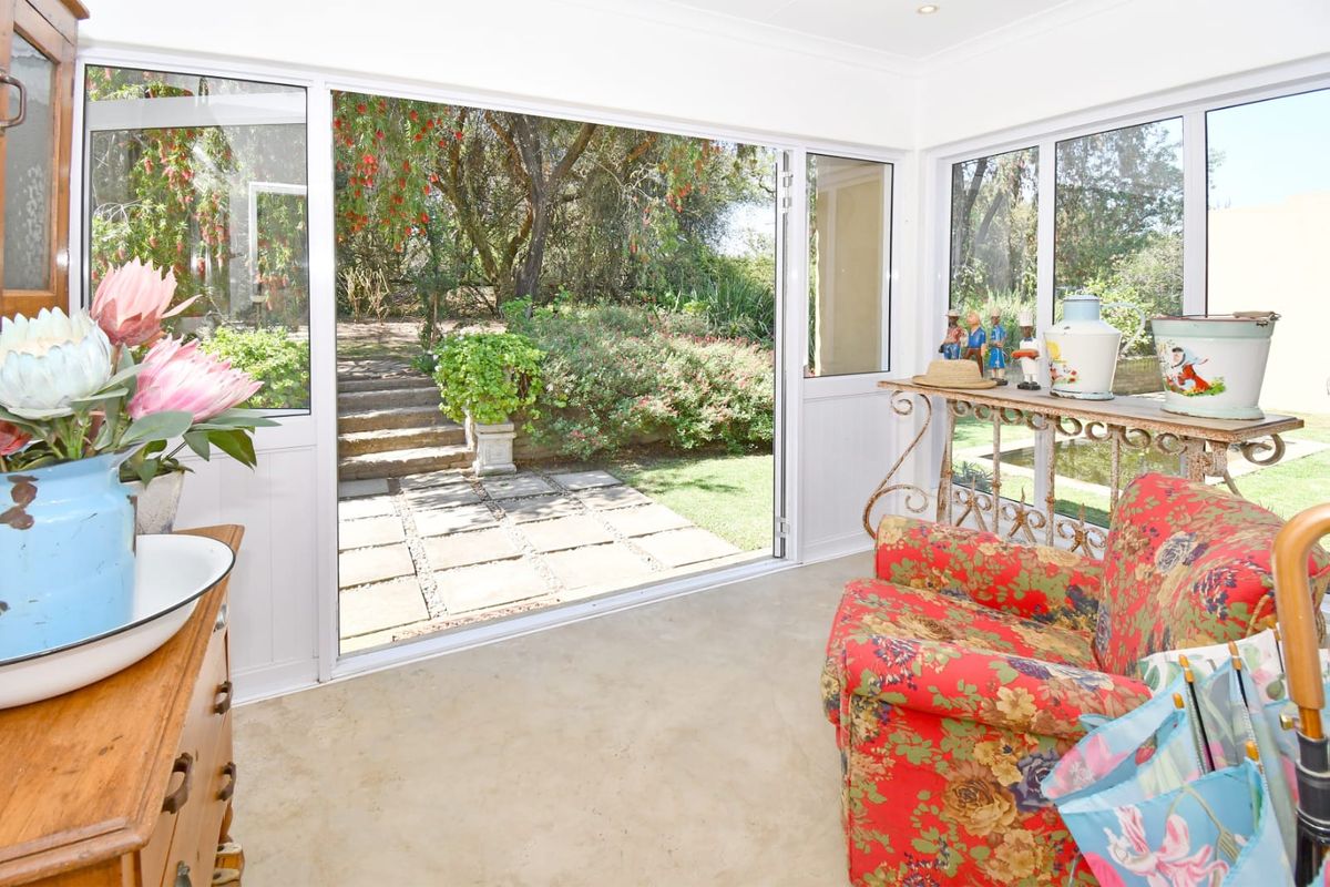 Bright living area featuring large sliding glass doors that open directly onto a paved patio and lush garden.