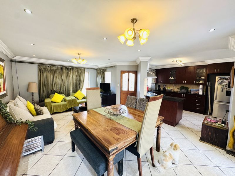 Spacious open-plan living, dining, and kitchen area featuring tiled floors, recessed lighting, and dark wood cabinetry with stone countertops.
