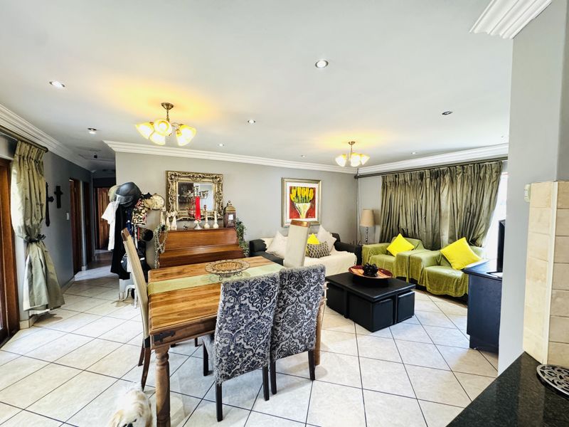 Spacious open-plan living and dining area featuring tiled flooring, recessed downlighting, and decorative ceiling cornices with access to outdoor space.