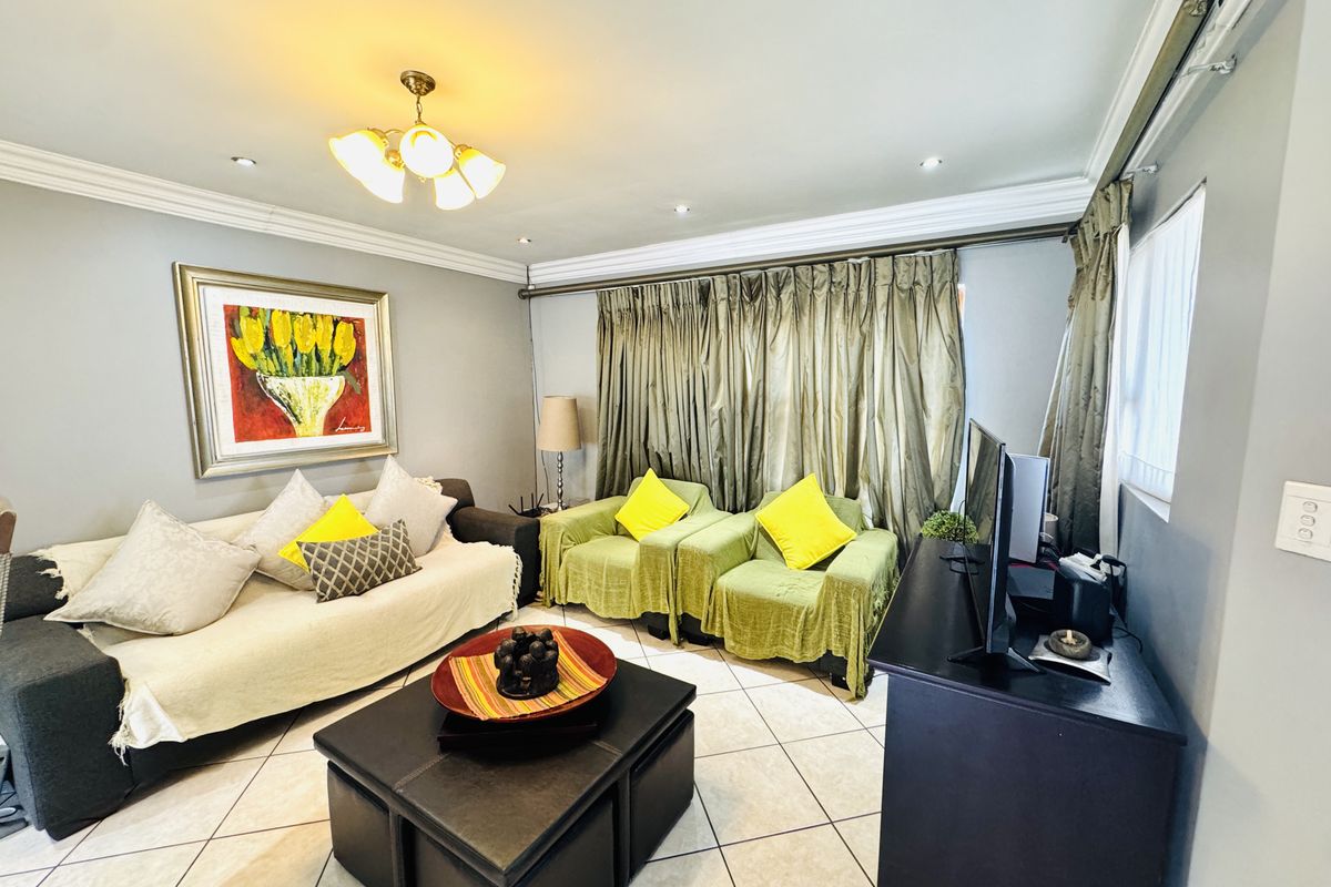 A comfortable living room featuring tiled flooring, crown molding, and recessed lighting, providing a functional and well-maintained space for relaxation.