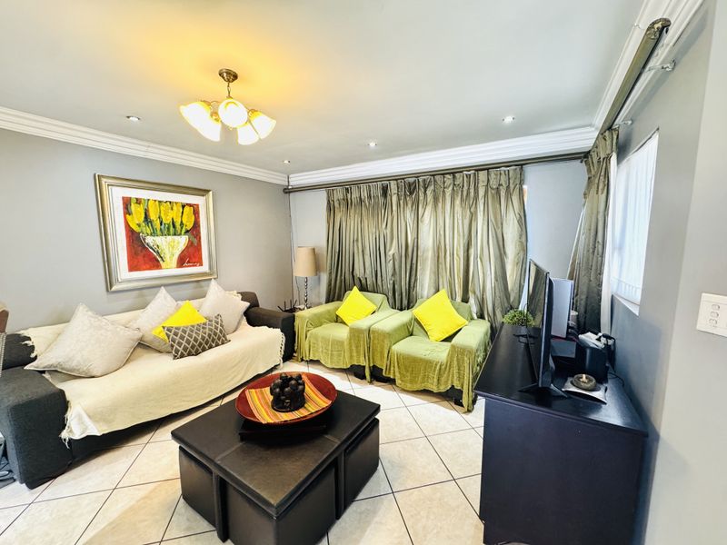 A comfortable living room featuring tiled flooring, crown molding, and recessed lighting, providing a functional and well-maintained space for relaxation.