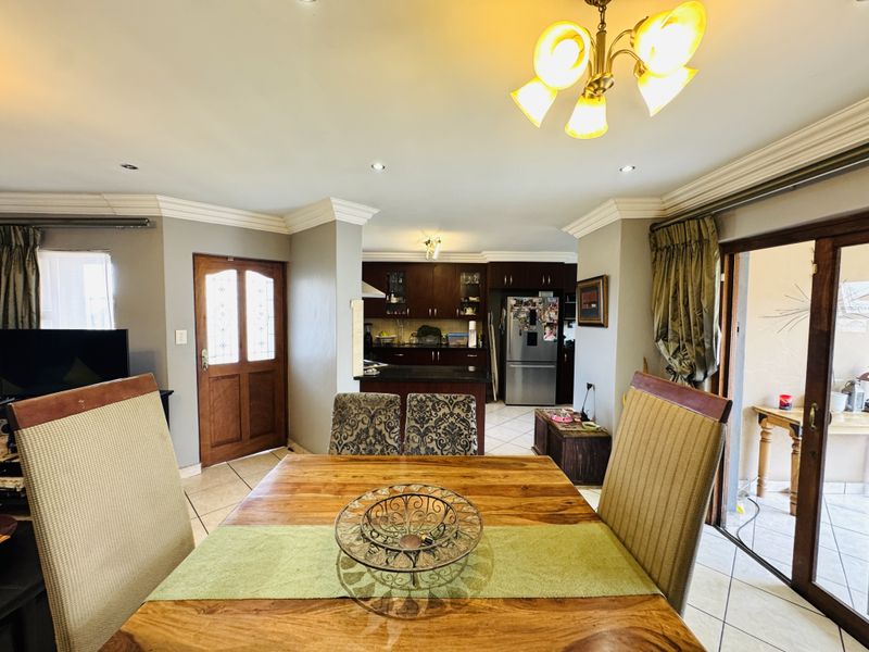 Open-plan dining and kitchen area featuring tiled floors, crown molding, and direct access to an outdoor patio through sliding glass doors.