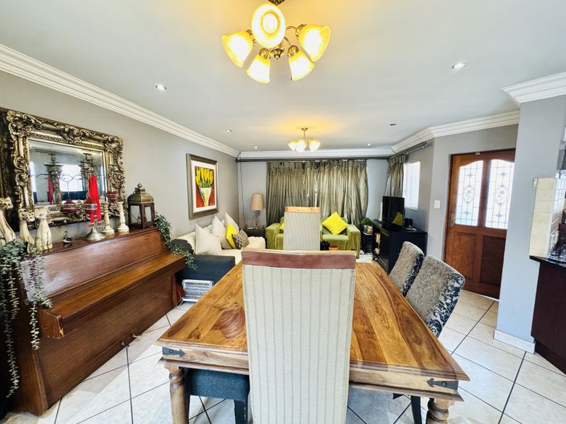 Open plan living and dining area featuring ceramic floor tiles, crown molding, and recessed lighting, creating a functional and connected living space.
