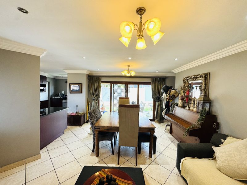 Open-plan living and dining area featuring tiled flooring, crown molding, and direct access to the rear patio through sliding glass doors.