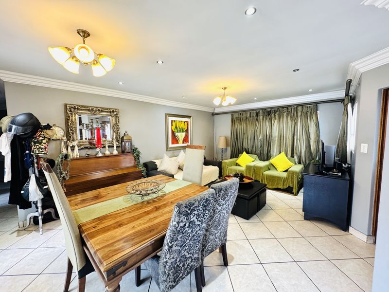 Spacious open-plan living and dining area featuring ceramic floor tiles, recessed downlighting, and decorative ceiling coving.