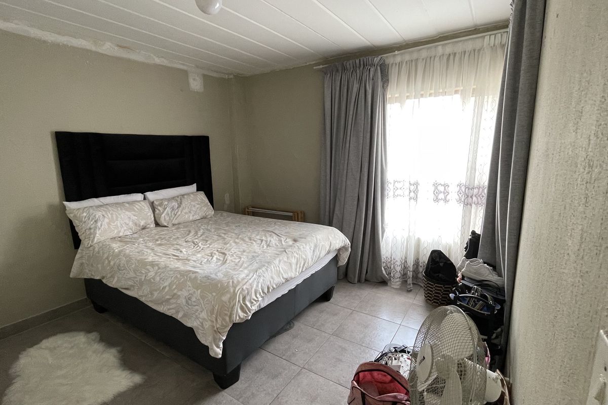 A bedroom featuring tiled flooring and ceiling panels, requiring cosmetic attention to the walls and ceiling finishes.