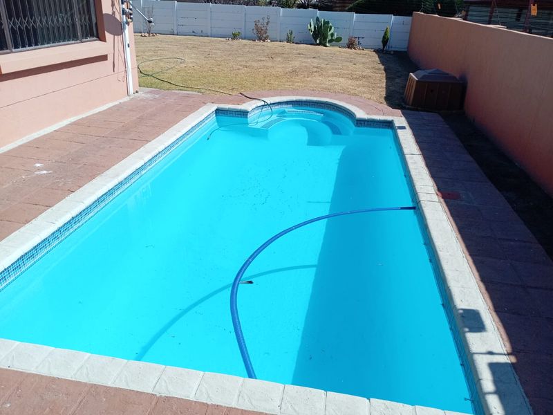 Outdoor swimming pool area featuring a paved surround and perimeter boundary walls, providing a private space for recreation.