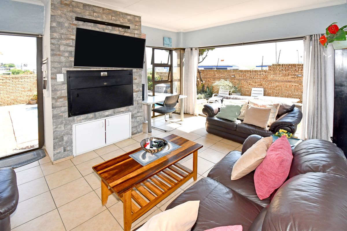 Spacious living room featuring a stone-clad fireplace wall, tiled flooring, and large sliding doors providing seamless access to the outdoor patio area.