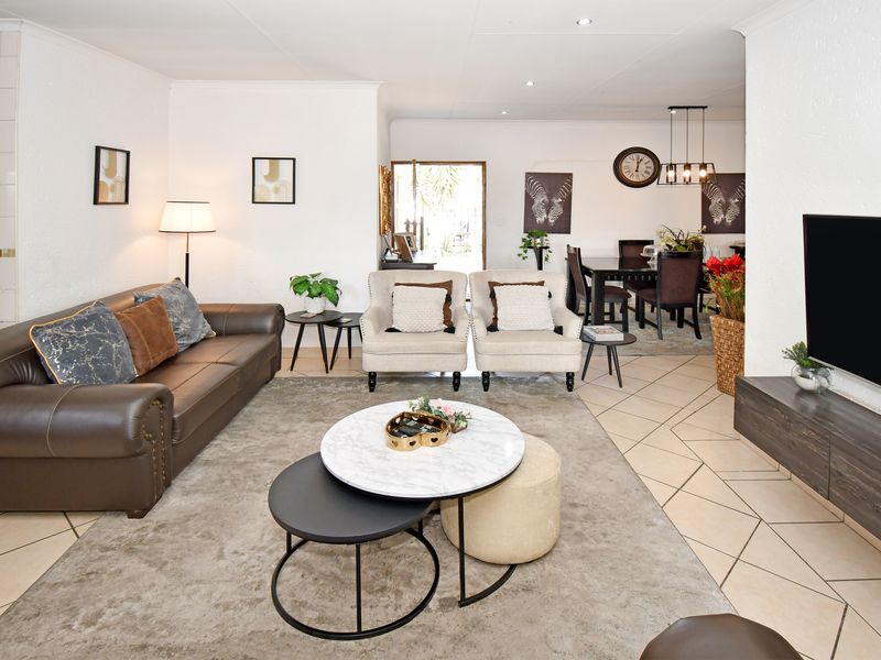 Spacious open-plan living and dining area featuring neutral tiled flooring, recessed lighting, and a seamless flow between the lounge and dining space.