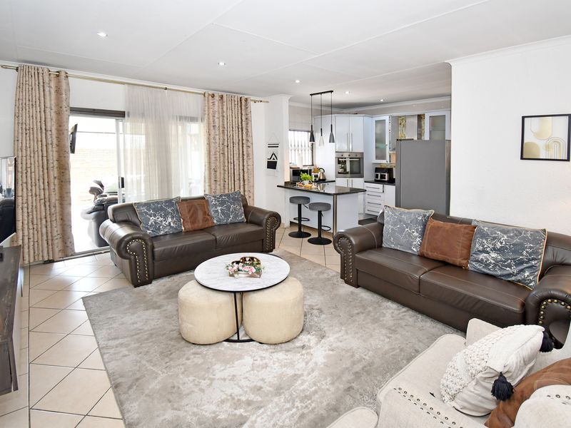 Spacious open-plan living area featuring tiled floors, recessed lighting, and a modern kitchen with a central island and built-in appliances.