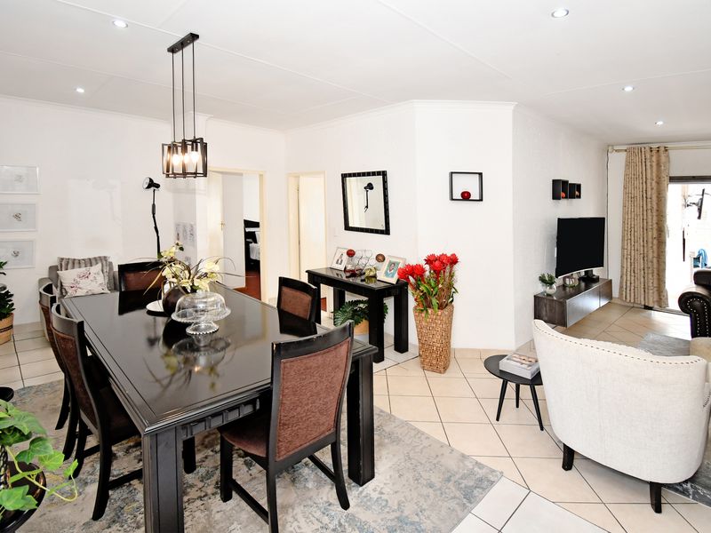 Spacious open-plan living and dining area featuring neutral ceramic floor tiles, recessed downlighting, and direct access to an outdoor patio through a sliding glass door.
