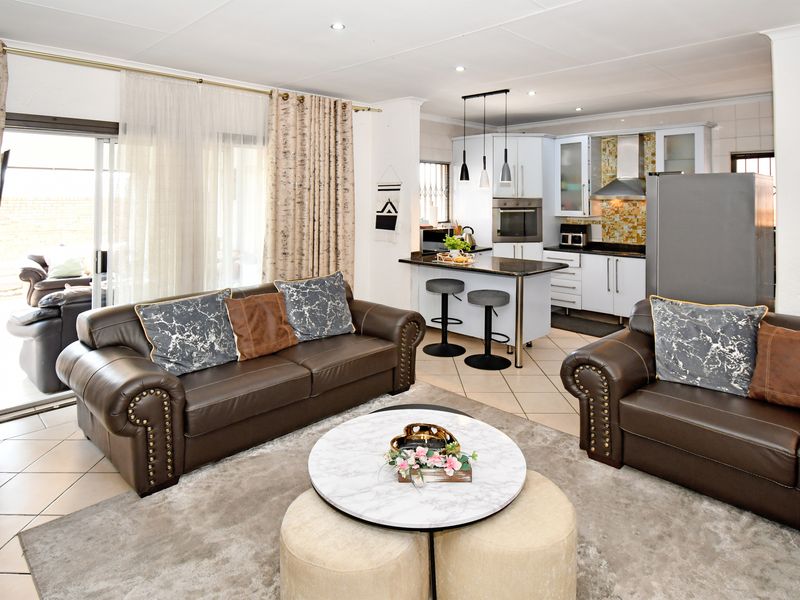 Spacious open-plan living area featuring a modern kitchen with granite countertops, built-in appliances, and seamless access to the outdoor patio through sliding glass doors.