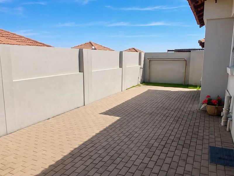 A clean and well-maintained paved rear courtyard featuring a high perimeter boundary wall and a fixed washing line.