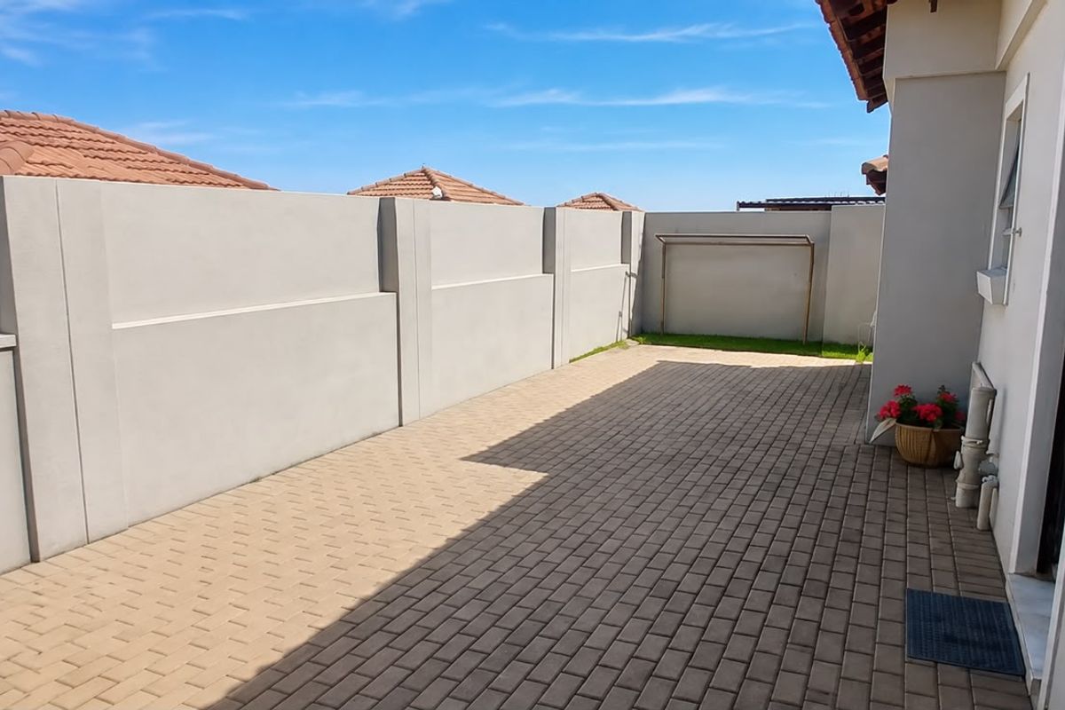 A clean and well-maintained paved rear courtyard featuring a high perimeter boundary wall and a fixed washing line.
