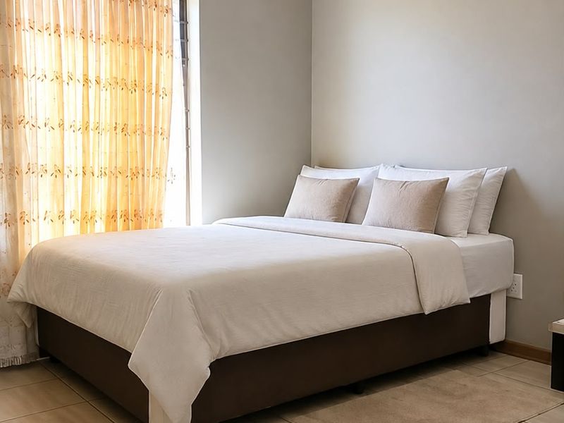 A well-maintained bedroom featuring neutral wall tones, tiled flooring, and classic ceiling cornicing, providing a clean and comfortable living space.