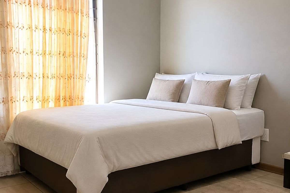 A well-maintained bedroom featuring neutral wall tones, tiled flooring, and classic ceiling cornicing, providing a clean and comfortable living space.
