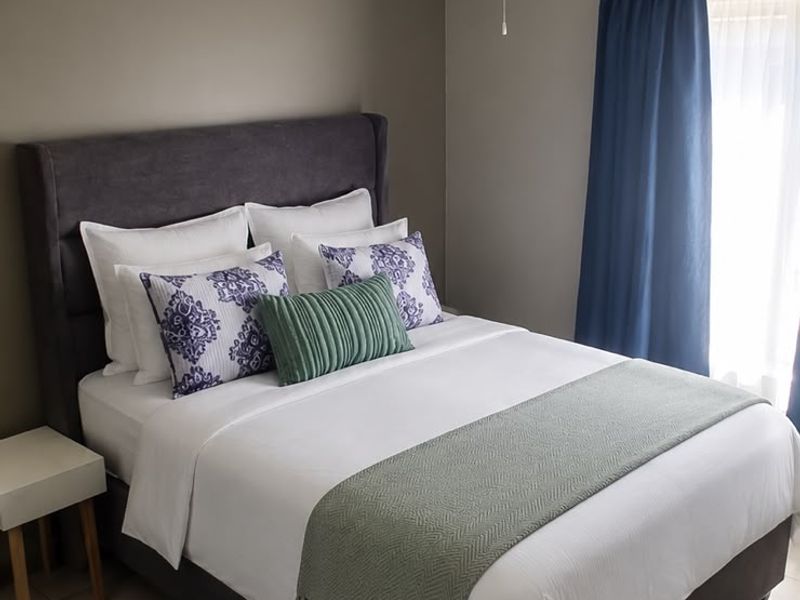 A well-maintained bedroom featuring neutral wall tones, tiled flooring, and a functional ceiling fan, providing a comfortable and clean living space.