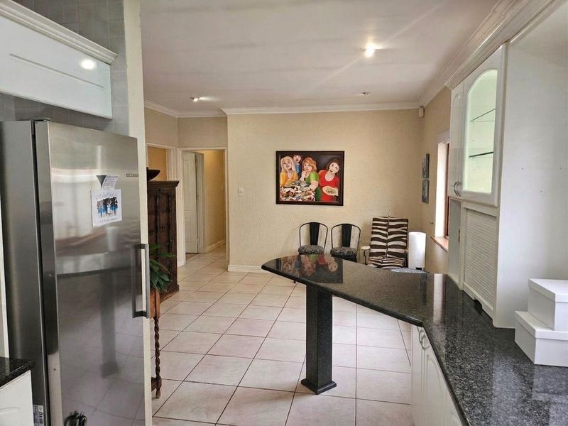 A functional kitchen featuring granite countertops, a breakfast bar, tiled flooring, and ample built-in cabinetry with a glass-front display unit.