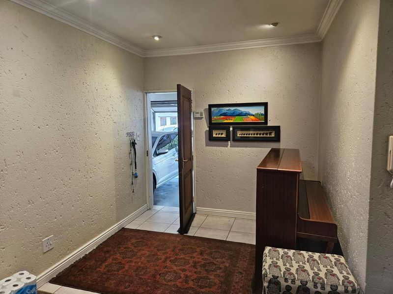 An entry hall featuring textured walls, tiled flooring, and recessed downlighting, providing a functional transition space into the home.