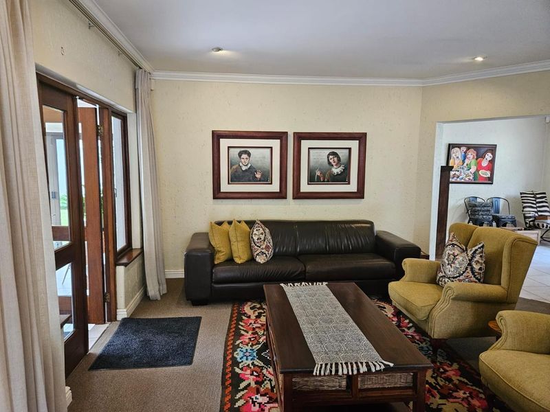 A comfortable living room featuring recessed downlighting, decorative cornicing, and direct access to the outdoor area through timber-framed glass doors.