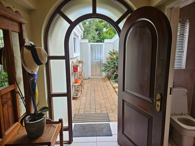 An entryway featuring an arched timber door opening onto a private brick-paved courtyard with a security gate.