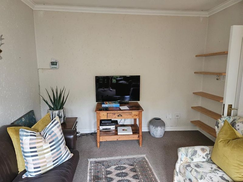 A living room featuring carpeted flooring, crown molding, and built-in wall shelving.